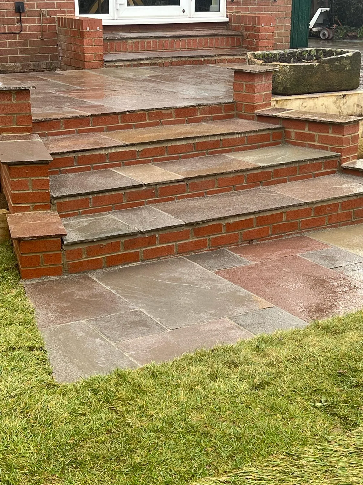 A brick patio with steps leading up to a door.